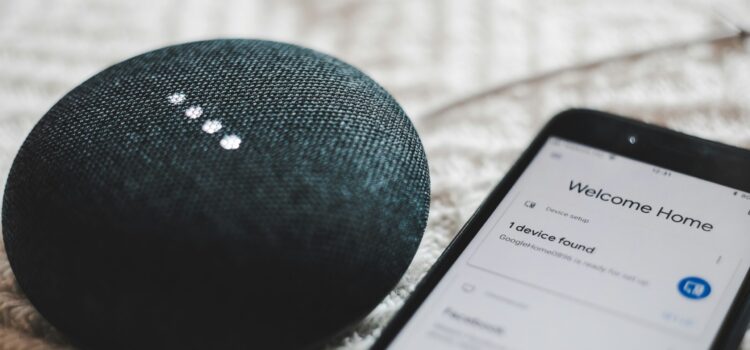 turned-on charcoal Google Home Mini and smartphone