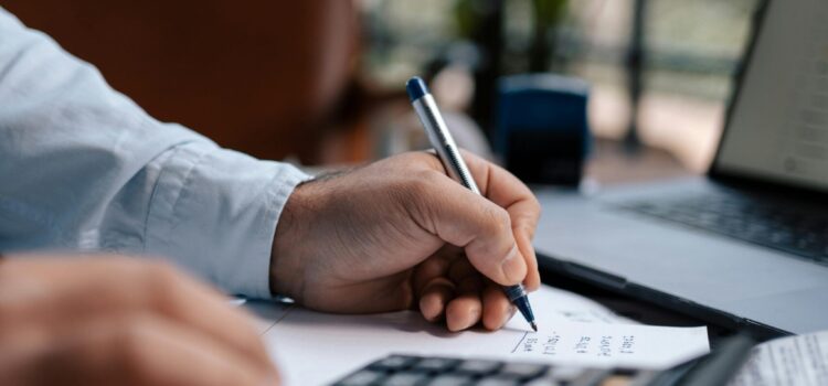 Free A person calculating finances with a calculator and pen on a desk indoors. Stock Photo
