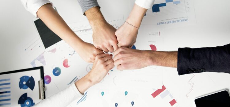 How Smart IT Boosts Employee Morale and Keeps Your Best People Free Colleagues celebrate success with a fist bump over financial charts depicting teamwork and unity. Stock Photo