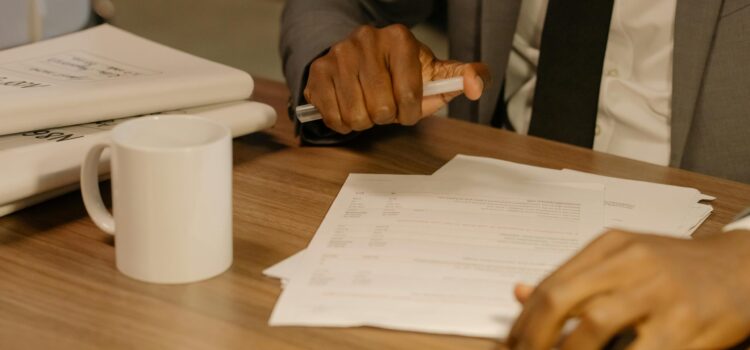 How to Answer Cyber Insurance Renewal Questions Without Voiding Your Policy Free Close-up of a businessman holding and reviewing documents on a wooden desk. Stock Photo