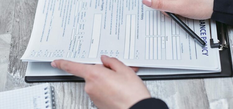 What Immutable Backup Means on Your Cyber Insurance Form Free Close-up of hands analyzing insurance policy paperwork with pen on table. Stock Photo