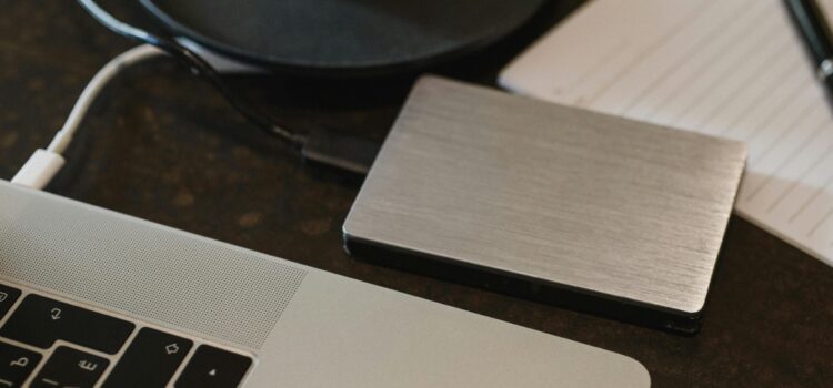 Free Closeup of an external hard drive connected to a laptop with a USB cable on a desk. Stock Photo